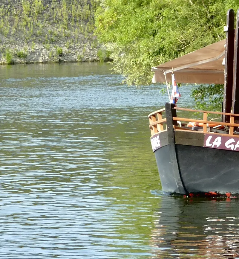 Proue de la gabare, bateau de promenade en bois, drapeau français, amarrée contre un quai de pierre.